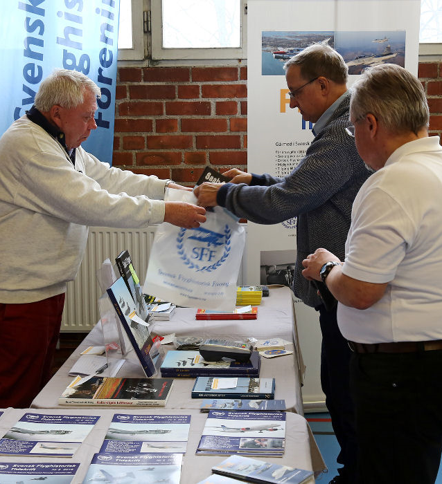 Lennart Berns och Bernt Olsson från SFF hjälper en besökare med ett köp av en bok i SFF:s monter. Foto: Gunnar Åkerberg  